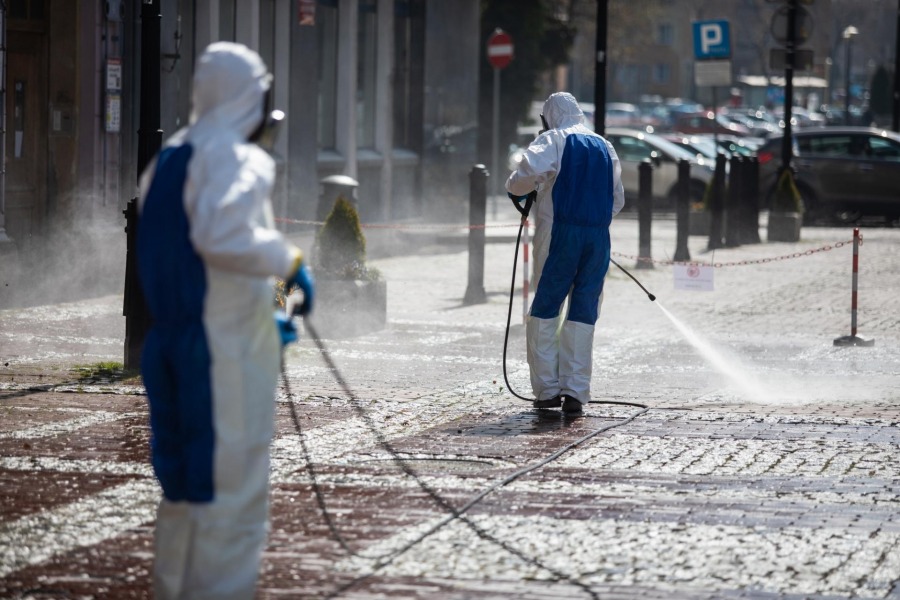 Ekipa w maskach i kombinezonach ochronnych w centrum miasta - foto