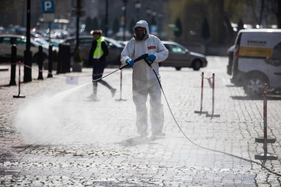 Ekipa w maskach i kombinezonach ochronnych w centrum miasta - foto